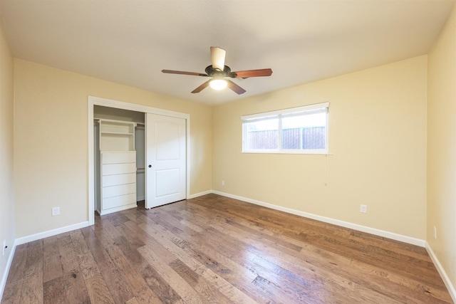 unfurnished bedroom with a ceiling fan, wood finished floors, baseboards, and a closet