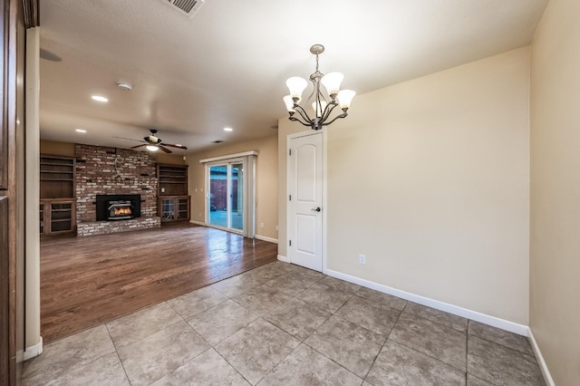 unfurnished living room with visible vents, baseboards, light tile patterned flooring, a fireplace, and ceiling fan with notable chandelier