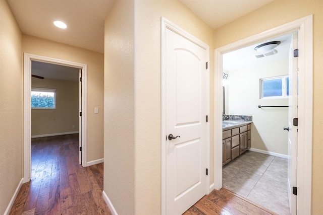 hallway featuring visible vents, baseboards, and wood finished floors