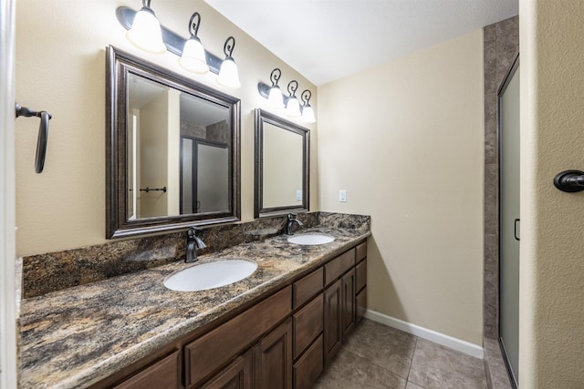 full bathroom featuring tile patterned flooring, double vanity, baseboards, and a sink