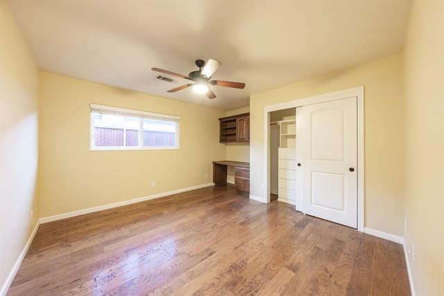 unfurnished bedroom with visible vents, a closet, light wood finished floors, baseboards, and built in study area