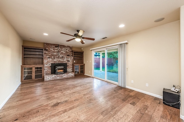 unfurnished living room with a ceiling fan, wood finished floors, visible vents, baseboards, and a fireplace