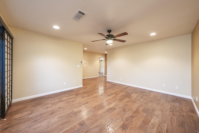 empty room with visible vents, light wood-style flooring, baseboards, and ceiling fan