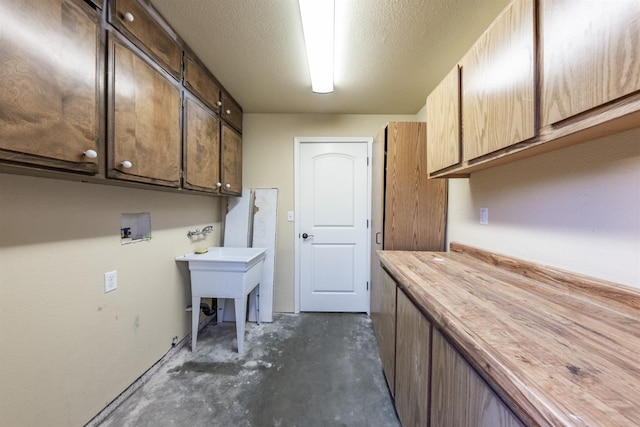 laundry area with cabinet space, a textured ceiling, and washer hookup