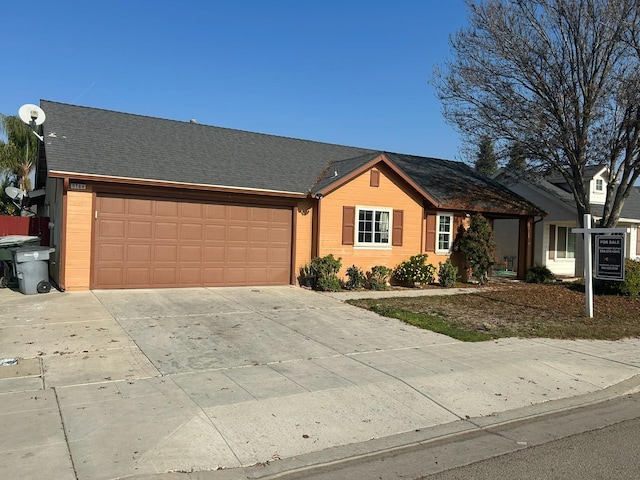 ranch-style house featuring a garage, roof with shingles, and driveway