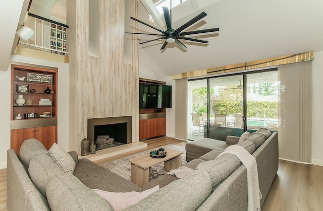 living room with baseboards, high vaulted ceiling, wood finished floors, and a fireplace