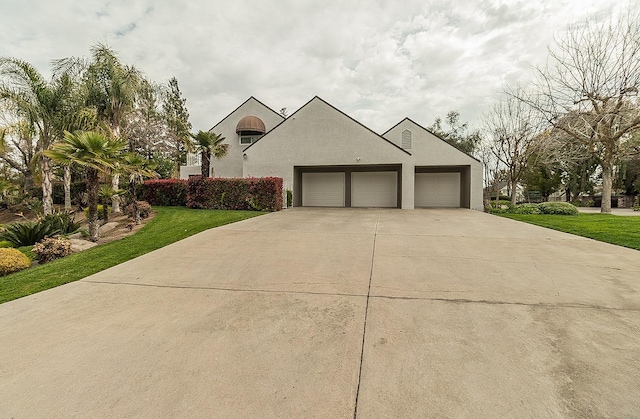 view of front of property with stucco siding, driveway, an attached garage, and a front yard