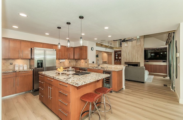 kitchen featuring a center island, beverage cooler, a peninsula, brown cabinetry, and stainless steel fridge