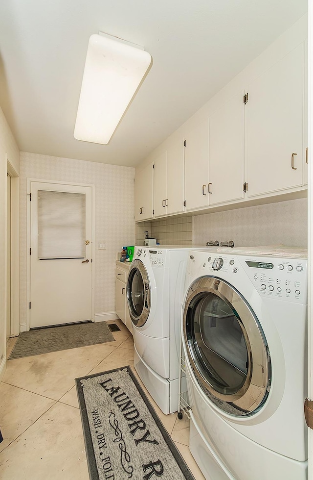 laundry area with light tile patterned floors, cabinet space, and washer and clothes dryer