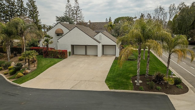 view of front of home featuring stucco siding, an attached garage, concrete driveway, and a front yard