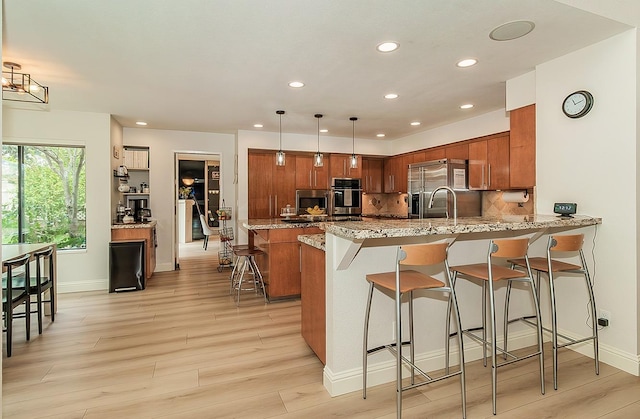 kitchen featuring a kitchen bar, a peninsula, brown cabinetry, and backsplash