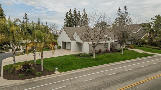 view of front of house featuring a garage, driveway, a front lawn, and stucco siding