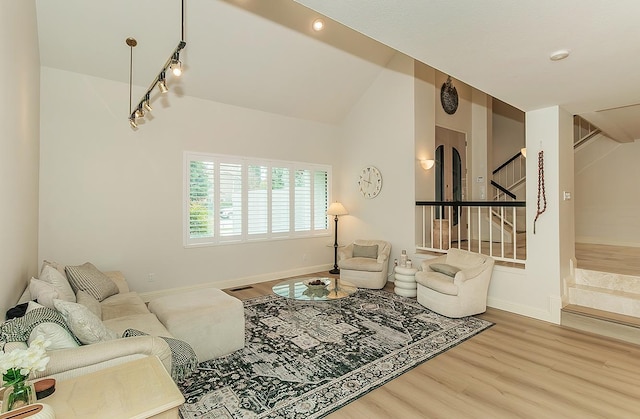 living room with stairway, baseboards, wood finished floors, and vaulted ceiling