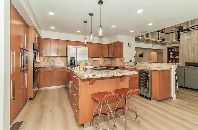 kitchen featuring beverage cooler, brown cabinets, stainless steel appliances, and a breakfast bar