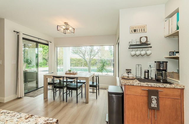 dining space featuring a healthy amount of sunlight, light wood-style flooring, and baseboards