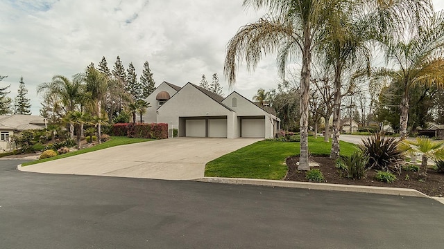 view of front of property featuring stucco siding, a front lawn, concrete driveway, and an attached garage