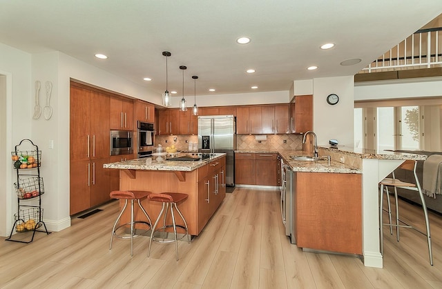 kitchen featuring brown cabinets, appliances with stainless steel finishes, a kitchen breakfast bar, and a sink