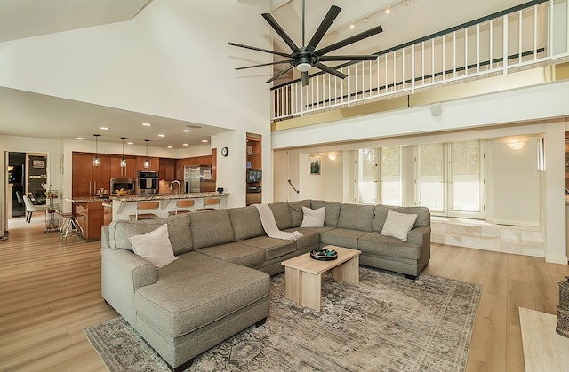 living room featuring recessed lighting, light wood-style flooring, a towering ceiling, and ceiling fan