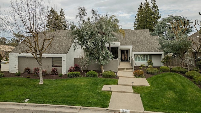 view of front of house with stucco siding, a front lawn, and fence