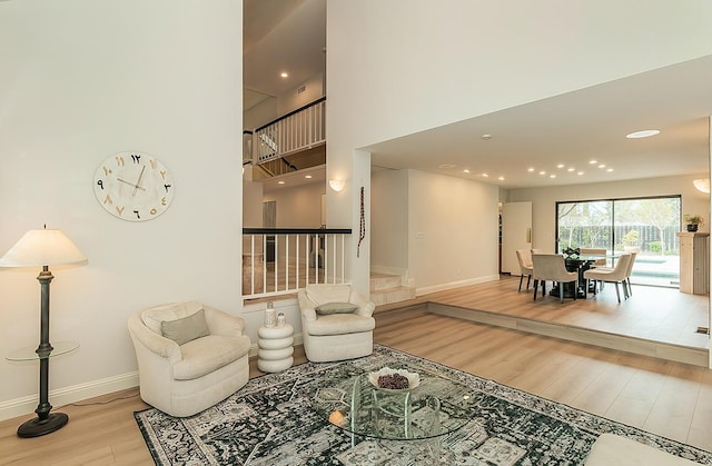 living room with a towering ceiling, baseboards, and wood finished floors