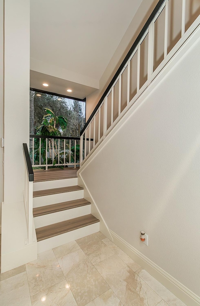 staircase with marble finish floor and baseboards