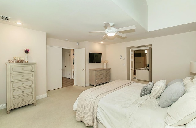 bedroom with visible vents, baseboards, light colored carpet, ensuite bath, and a ceiling fan