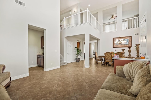 living room featuring stairs, visible vents, ceiling fan with notable chandelier, and baseboards