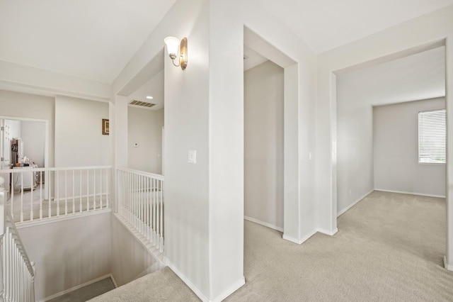 corridor with an upstairs landing, baseboards, and carpet floors