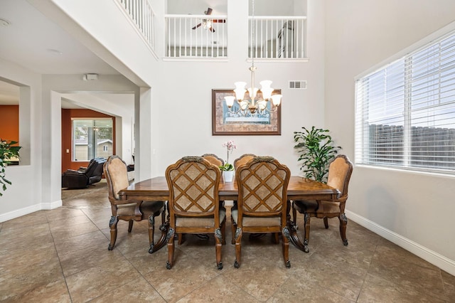 dining room with a notable chandelier, visible vents, baseboards, and a towering ceiling