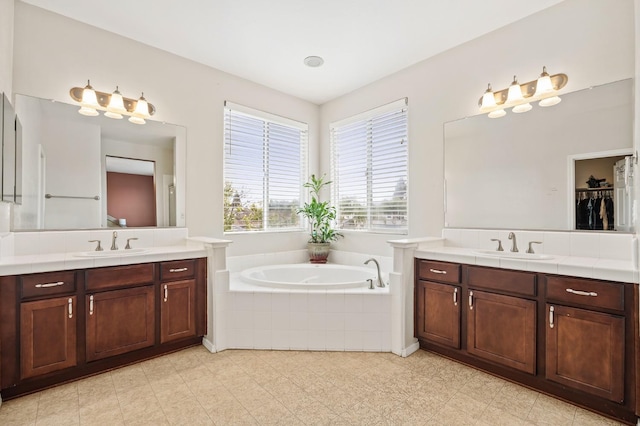 bathroom with a bath, two vanities, and a sink