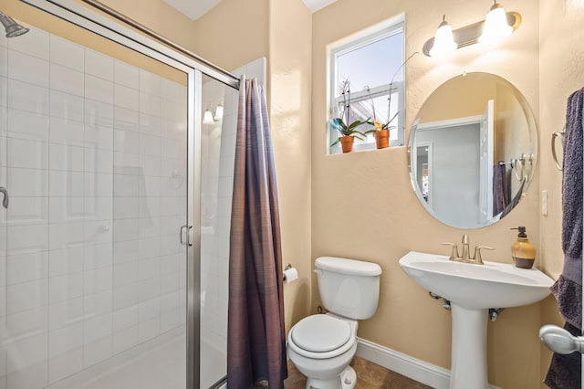 bathroom featuring a shower stall, toilet, and baseboards