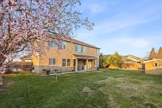 rear view of house featuring a lawn, a fenced backyard, and stucco siding