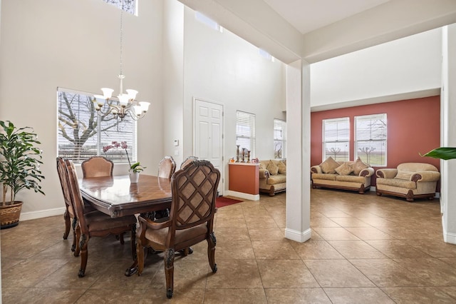 dining space featuring light tile patterned floors, a notable chandelier, baseboards, and a towering ceiling