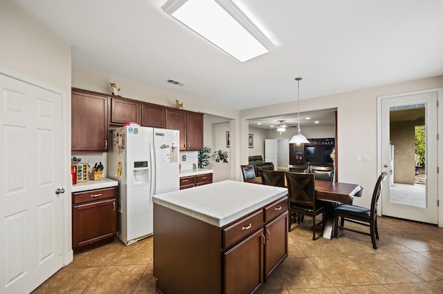 1410 Azalea St, Kingsburg, CA 93631 - kitchen featuring white fridge with ice dispenser, tile countertops, pendant lighting, a center island, and light tile patterned floors