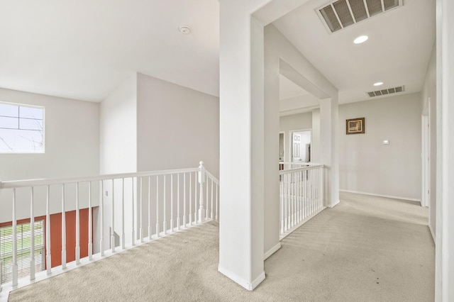 hallway featuring visible vents, baseboards, and carpet