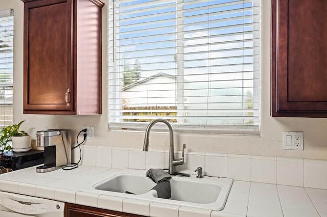 kitchen with tile countertops, white dishwasher, reddish brown cabinets, and a sink