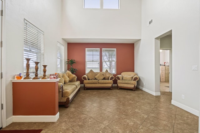 living area with a high ceiling, baseboards, and visible vents