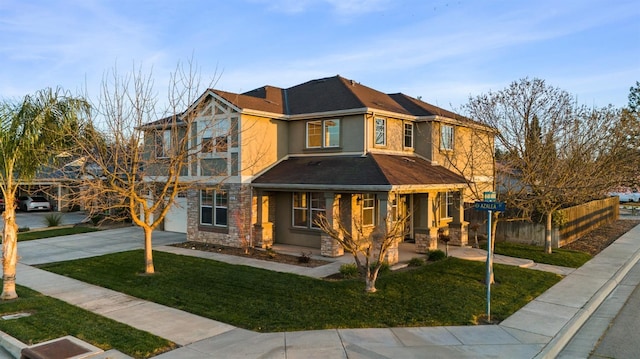 view of front facade featuring stucco siding, driveway, stone siding, fence, and a front yard