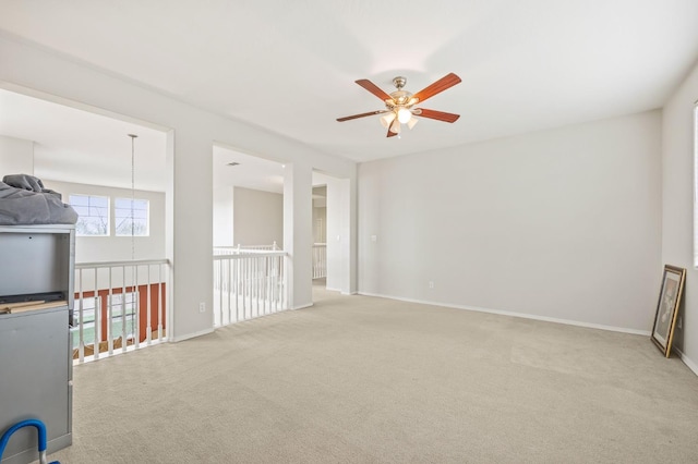 carpeted empty room with baseboards and a ceiling fan