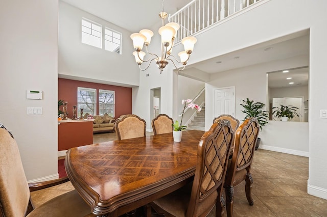 dining area featuring baseboards, a high ceiling, and stairs