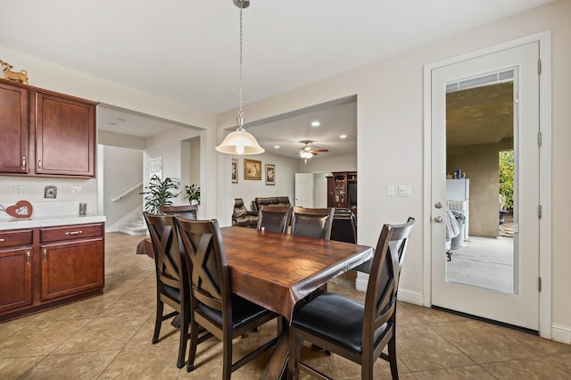 dining space with light tile patterned floors, baseboards, and stairs