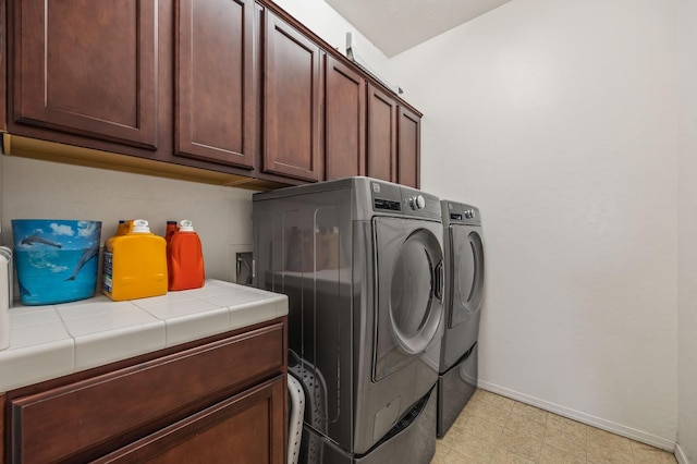 laundry area featuring cabinet space, baseboards, light floors, and washing machine and clothes dryer