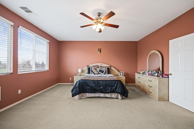 carpeted bedroom with visible vents, baseboards, and a ceiling fan