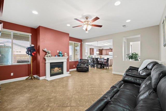 living area with a glass covered fireplace, recessed lighting, a ceiling fan, and baseboards