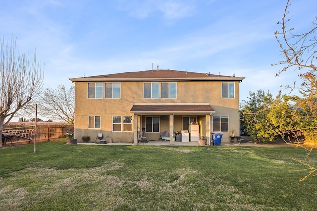 rear view of property with a yard, a patio, stucco siding, and fence