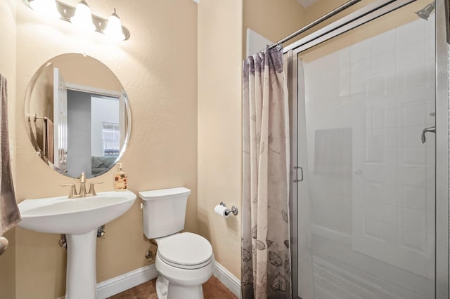 bathroom featuring a stall shower, toilet, and baseboards