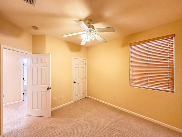 unfurnished bedroom featuring light colored carpet, baseboards, and ceiling fan