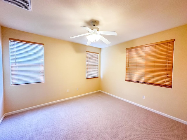 unfurnished room with carpet flooring, baseboards, visible vents, and ceiling fan