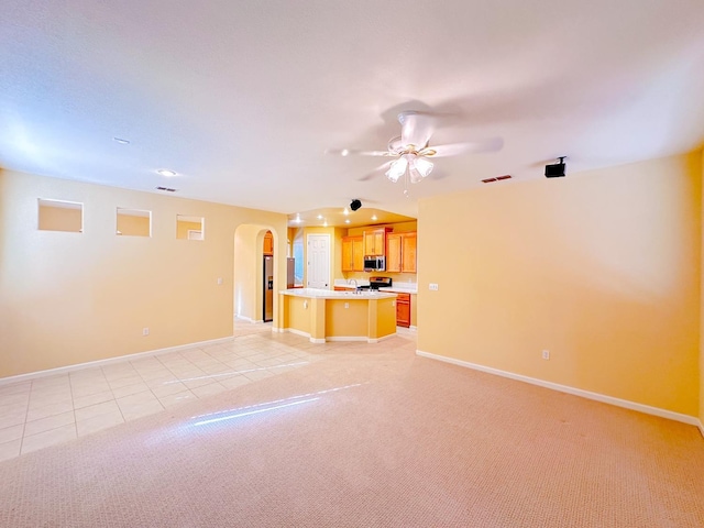 unfurnished living room with visible vents, baseboards, light tile patterned flooring, arched walkways, and light colored carpet