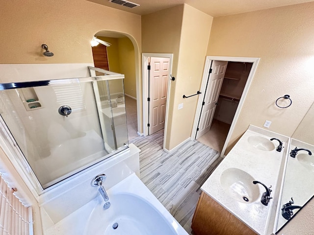 bathroom featuring a bath, a shower stall, wood finished floors, and a sink